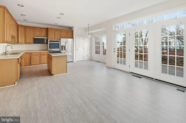 a large kitchen with stainless steel appliances wooden floors and white cabinets