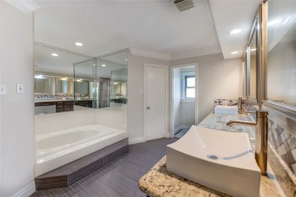 a spacious bathroom with a tub double vanity and a mirror