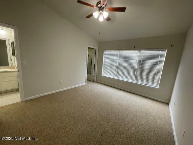 an empty room with windows and fan