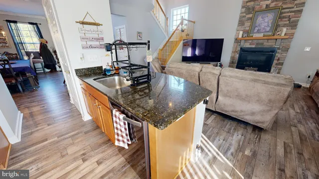 a kitchen with stainless steel appliances granite countertop a sink a stove and a wooden floors