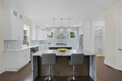 a kitchen with stainless steel appliances granite countertop a table chairs sink refrigerator and cabinets