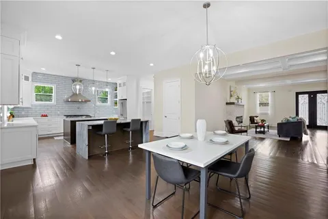 a view of a dining room and livingroom with furniture wooden floor a chandelier