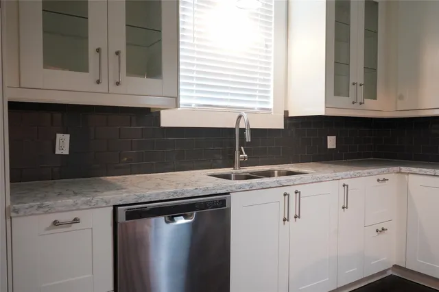 a kitchen with granite countertop white cabinets and a sink
