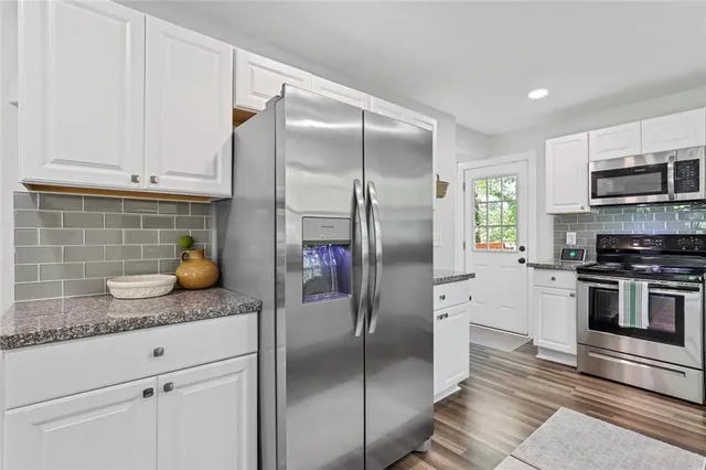 a kitchen with stainless steel appliances granite countertop a refrigerator a stove and a sink with wooden floor