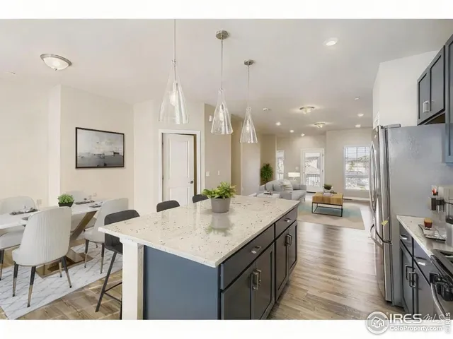 a open kitchen with stainless steel appliances kitchen island granite countertop a dining table chairs and white cabinets