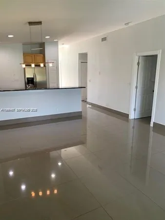 a view of a hallway to a room and kitchen