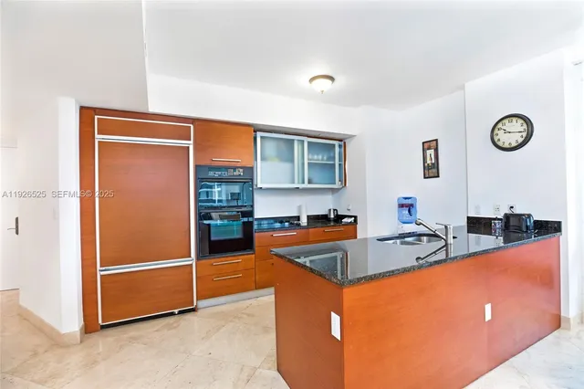a kitchen with stainless steel appliances granite countertop a sink and a refrigerator