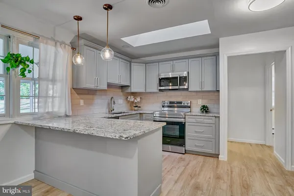 a kitchen with kitchen island granite countertop a sink appliances cabinets and a potted plant