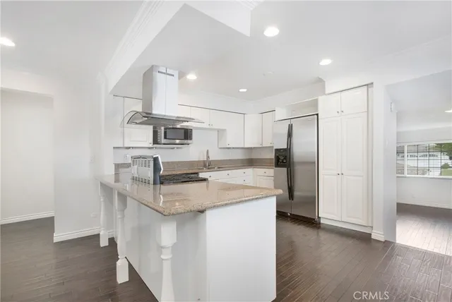 a kitchen with stainless steel appliances granite countertop a kitchen island hardwood floor and a sink