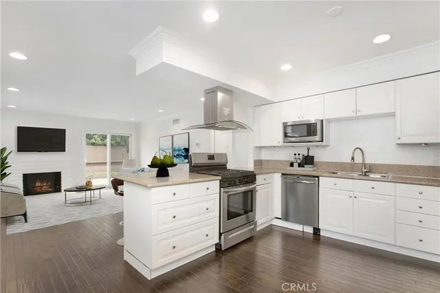 a kitchen with stainless steel appliances sink stove refrigerator and wooden floor