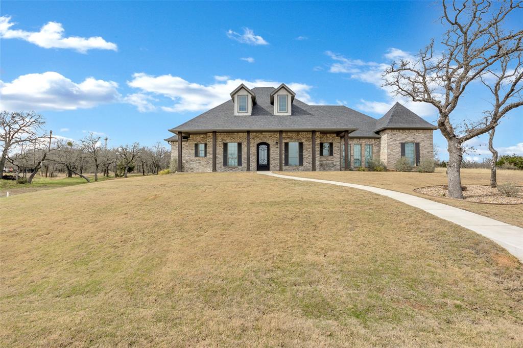 View of front of property featuring brick siding, roof with shingles, and a front yard