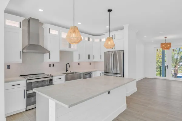 a kitchen with stainless steel appliances a stove a sink a center island and a wooden floor