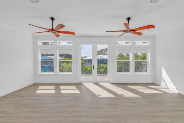 a view of an empty room with wooden floor and windows