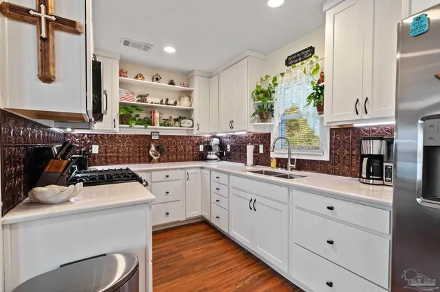 a kitchen with granite countertop a refrigerator and a wooden floor