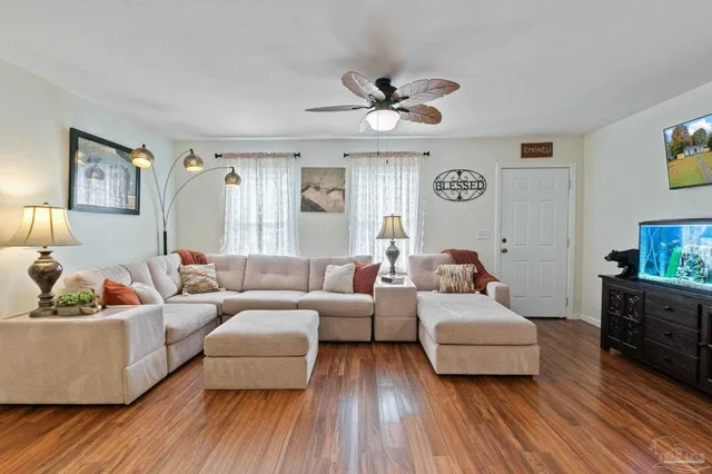 a kitchen with stainless steel appliances granite countertop a refrigerator a sink a stove and white cabinets with wooden floor