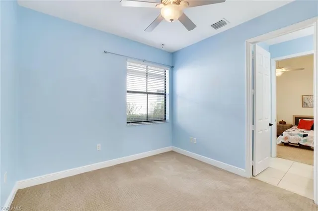 an empty room with a window and a chandelier fan