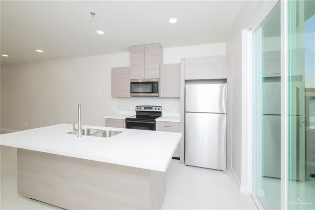 a kitchen with kitchen island a sink stainless steel appliances and refrigerator