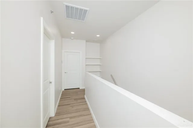 a view of a hallway with wooden floor and staircase