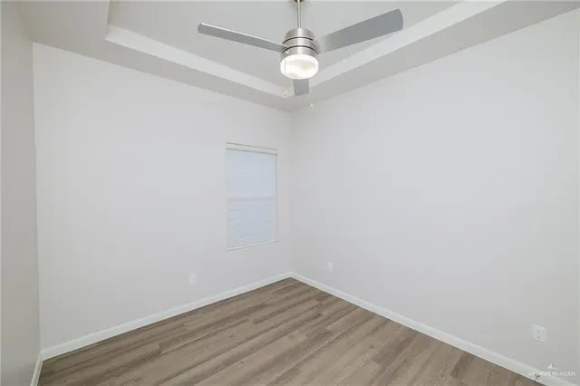 an empty room with wooden floor and fan