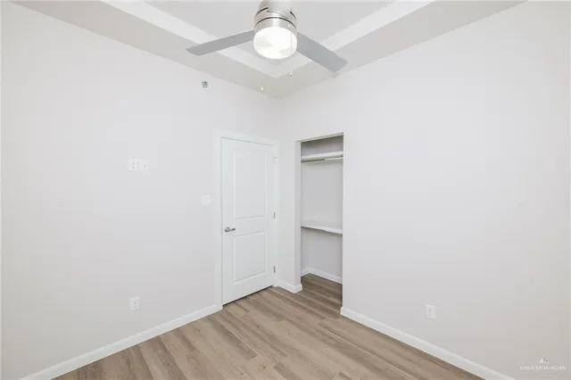 an empty room with wooden floor and ceiling fan
