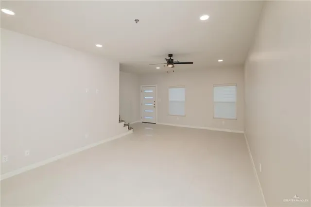 an empty room with chandelier fan and windows