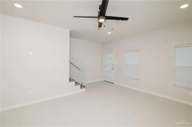 an empty room with a ceiling fan and carpet