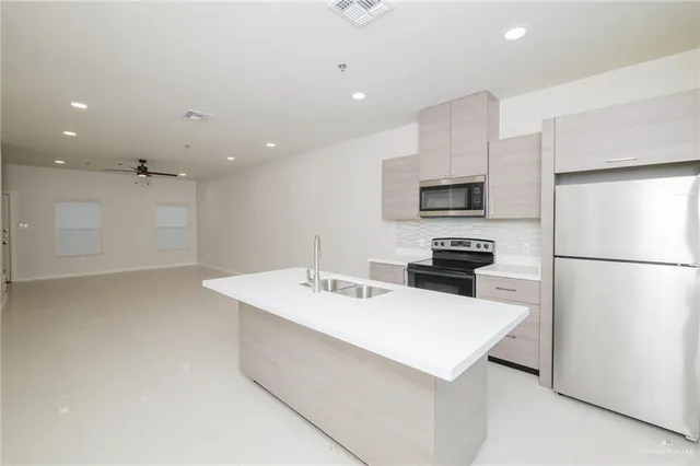 a kitchen with a sink a refrigerator and a stove top oven