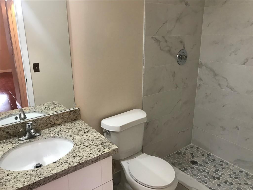 9781 Riverside Drive, Unit 653 Coral Springs, FL 33071 - Photo 16 of 19 a bathroom with a granite countertop sink a toilet and a mirror