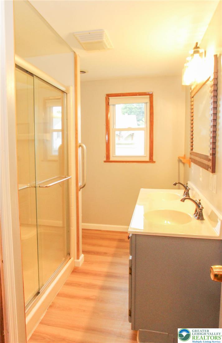 492 Filetown Road Nazareth, PA 18064 - Photo 17 of 30 A sleek vanity with dual sinks, warm wood flooring, and a glass-enclosed shower create a practical bathroom retreat.