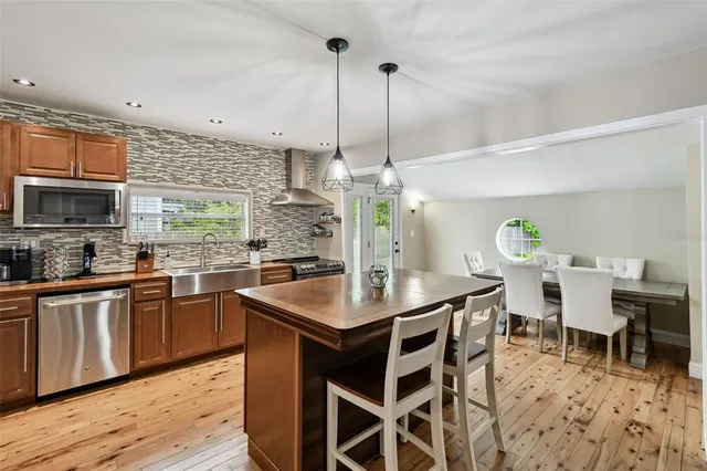 a kitchen with stainless steel appliances kitchen island granite countertop a table chairs sink and cabinets