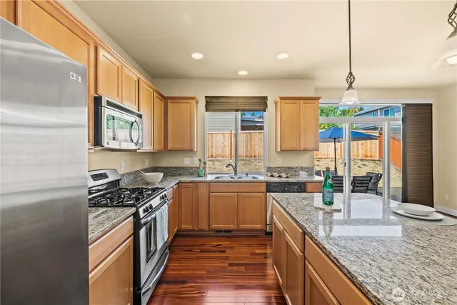 a kitchen with stainless steel appliances granite countertop a stove a sink and a refrigerator