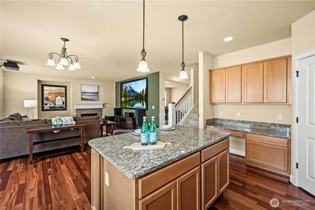 a kitchen with kitchen island granite countertop a stove a sink and dishwasher wooden cabinets with wooden floor