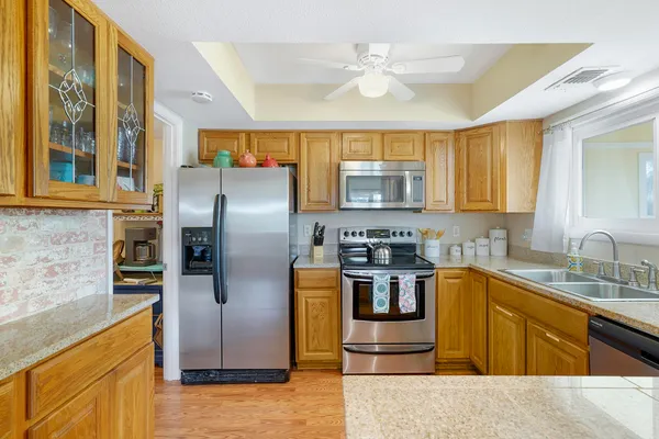 a view of a kitchen counter top space with stainless steel appliances wooden floor and large windows