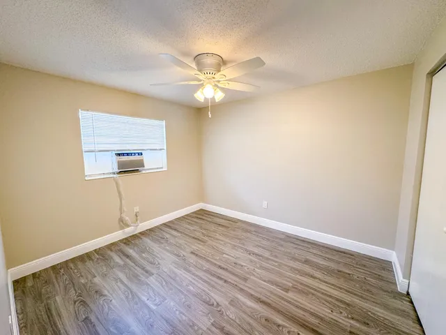 a view of an empty room with window and wooden floor