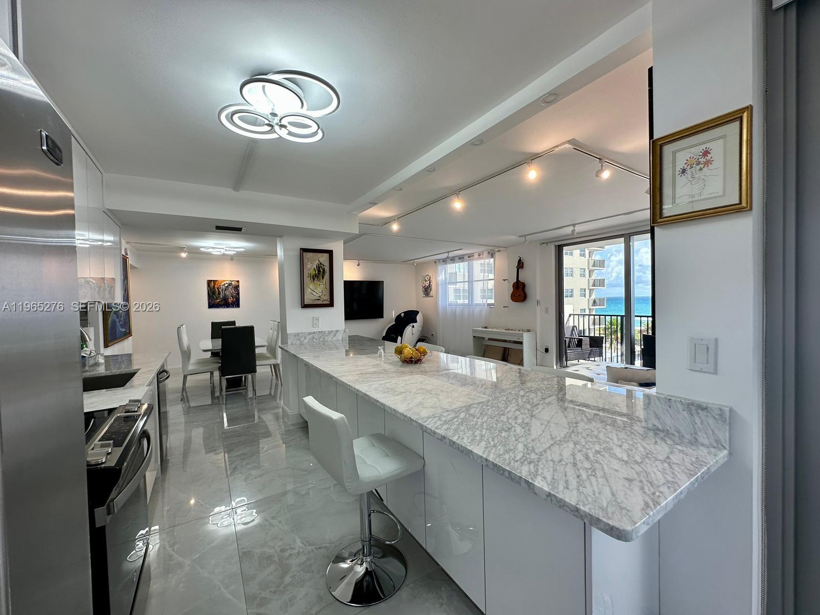9273 Collins Avenue, Unit 412 Surfside, FL 33154 - Photo 2 of 10 a kitchen with center island a sink appliances and a counter top space