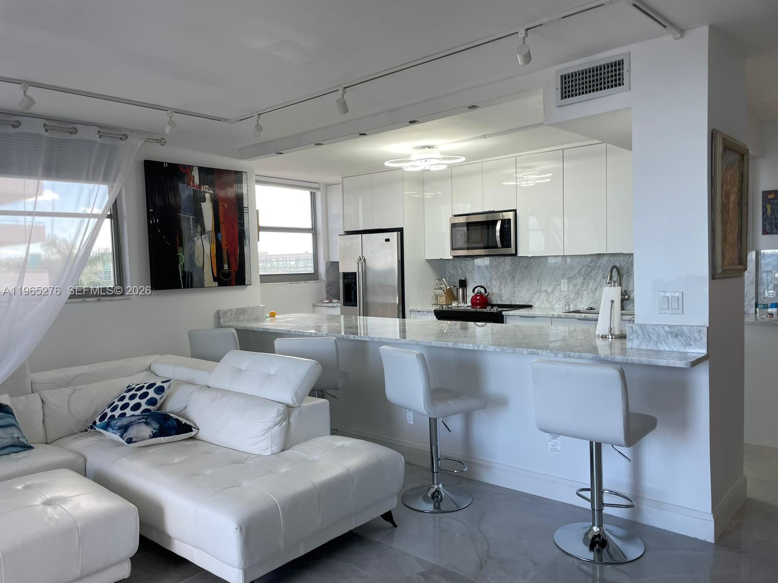 9273 Collins Avenue, Unit 412 Surfside, FL 33154 - Photo 4 of 10 a living room with furniture and a flat screen tv