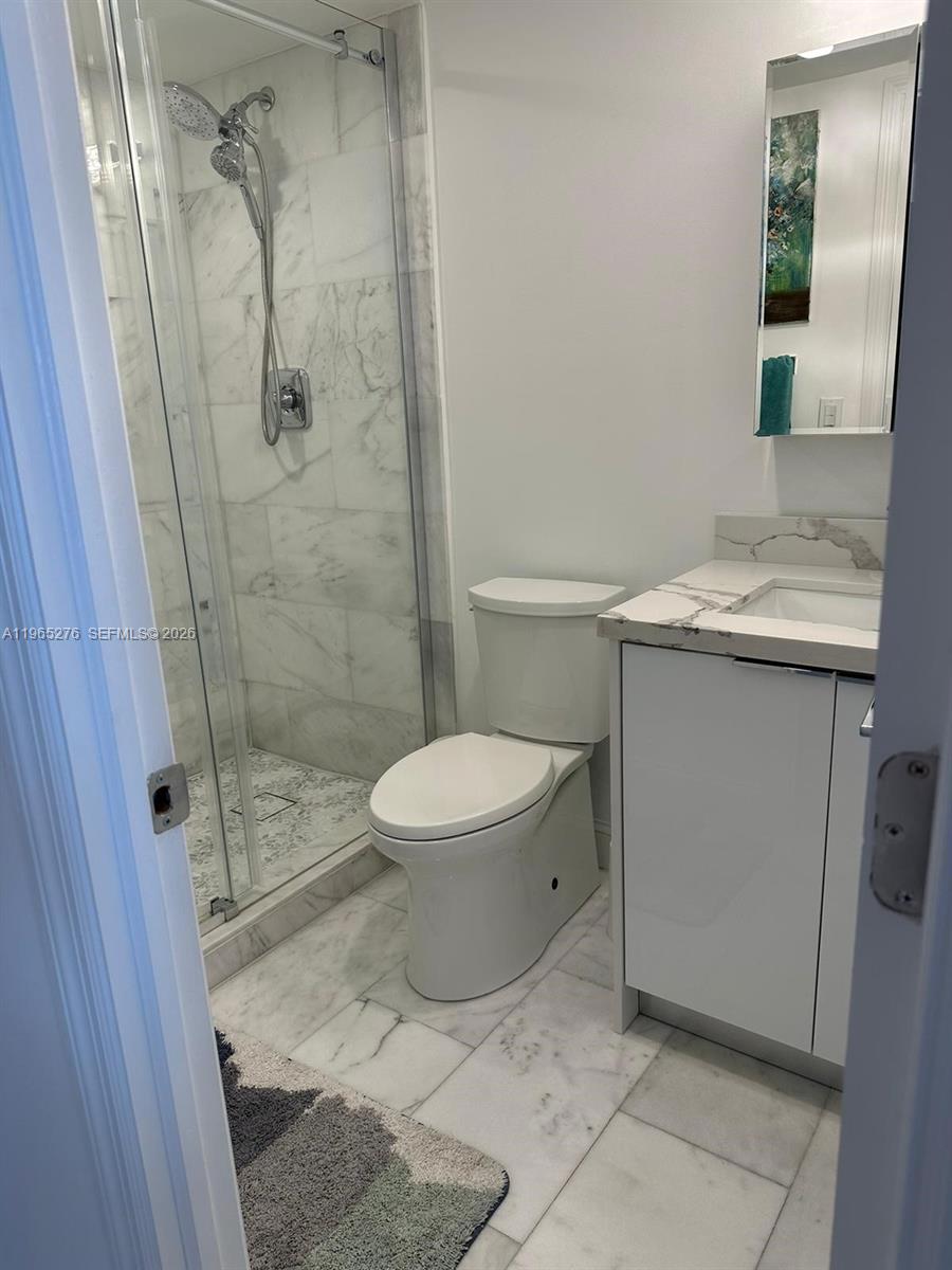 9273 Collins Avenue, Unit 412 Surfside, FL 33154 - Photo 9 of 10 a bathroom with a granite countertop sink a toilet and shower