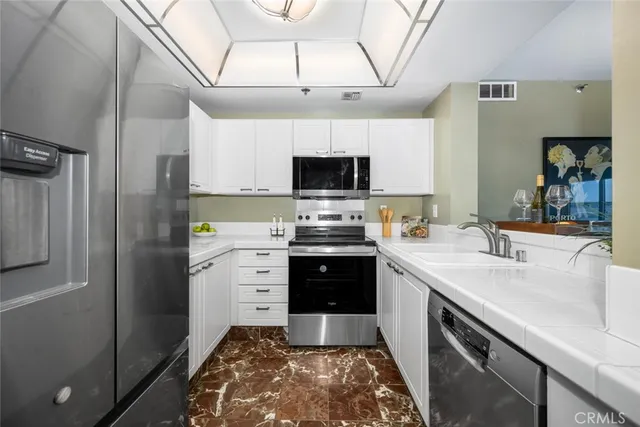 a view of a kitchen counter top space with stainless steel appliances granite countertop a stove and a sink