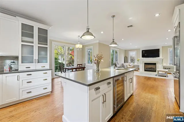 a kitchen with stainless steel appliances granite countertop a refrigerator a sink dishwasher a stove and white cabinets with wooden floor