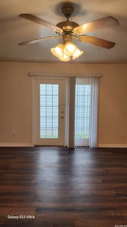 a view of an empty room with window and wooden floor