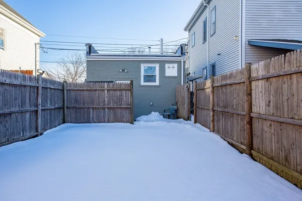 a view of backyard with wooden fence and a large window