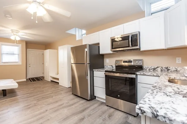 a kitchen with granite countertop a refrigerator and a stove top oven