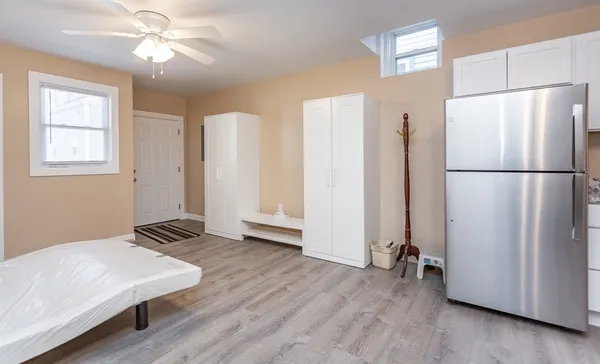 a view of a refrigerator in kitchen and an empty room with wooden floor windows