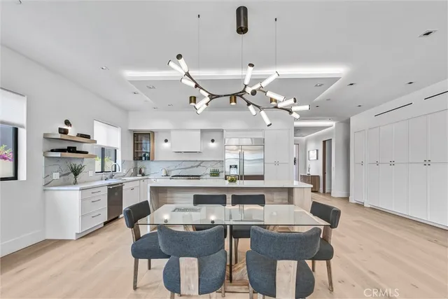 a dining room with stainless steel appliances kitchen island granite countertop a table chairs and a chandelier
