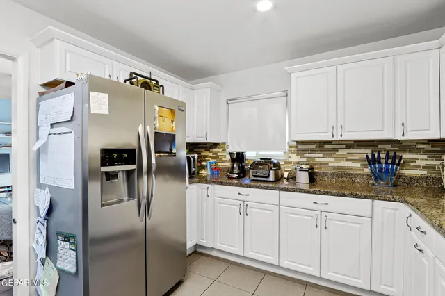 a kitchen with stainless steel appliances granite countertop a refrigerator a stove and white cabinets
