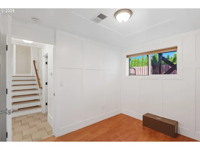 a view of an empty room with wooden floor and stairs