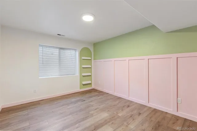 an empty room with wooden floor and windows
