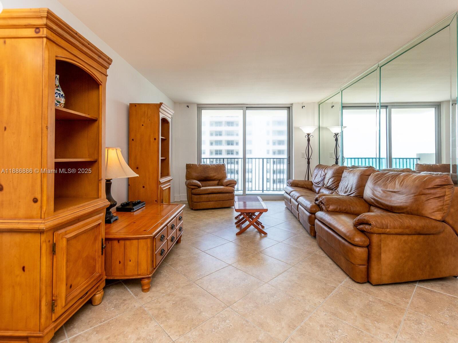 9273 Collins Avenue, Unit 703 Surfside, FL 33154 - Photo 2 of 49 a living room with furniture gym equipment and a large window