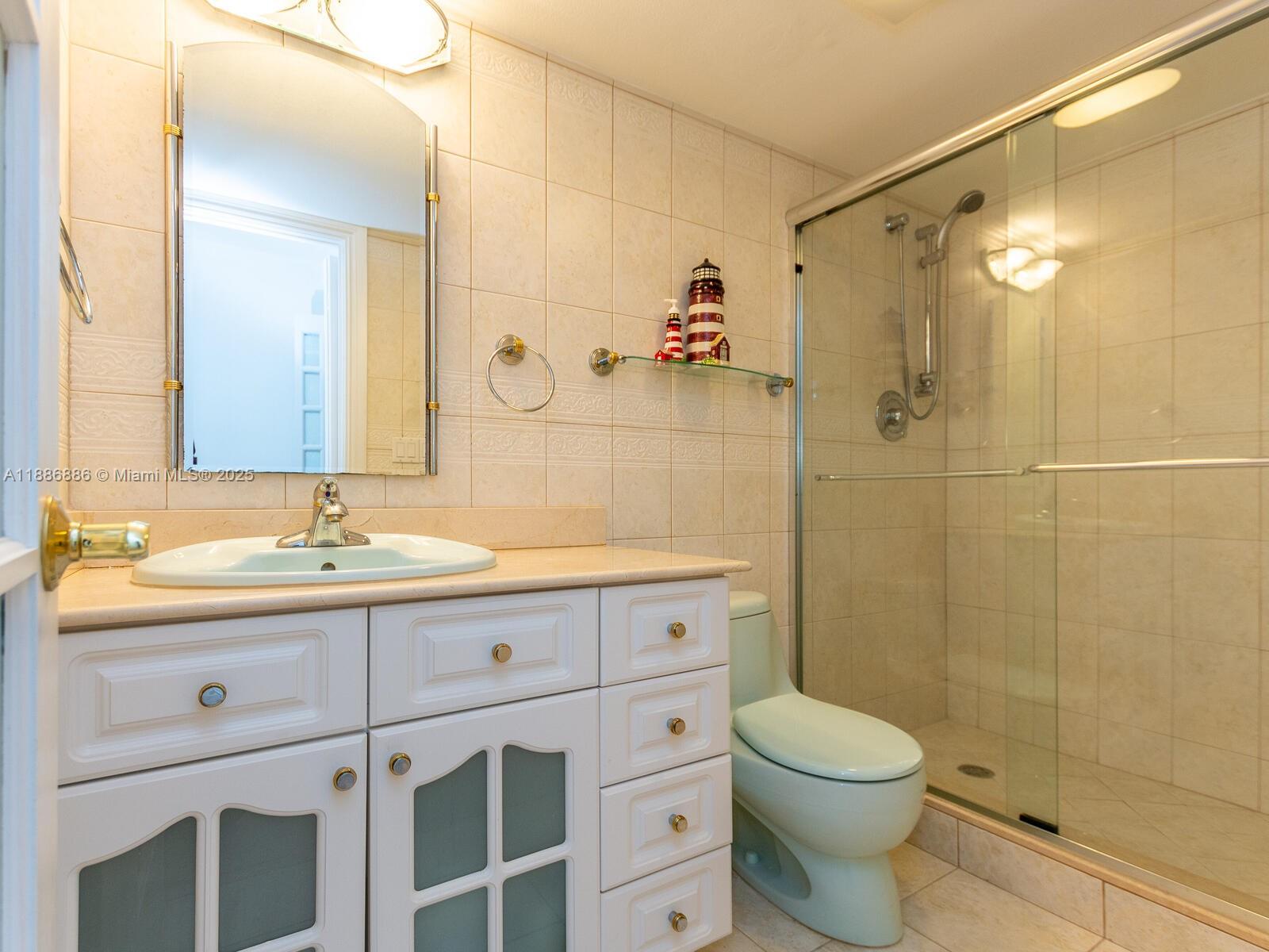 9273 Collins Avenue, Unit 703 Surfside, FL 33154 - Photo 23 of 49 a bathroom with a granite countertop sink a toilet and shower