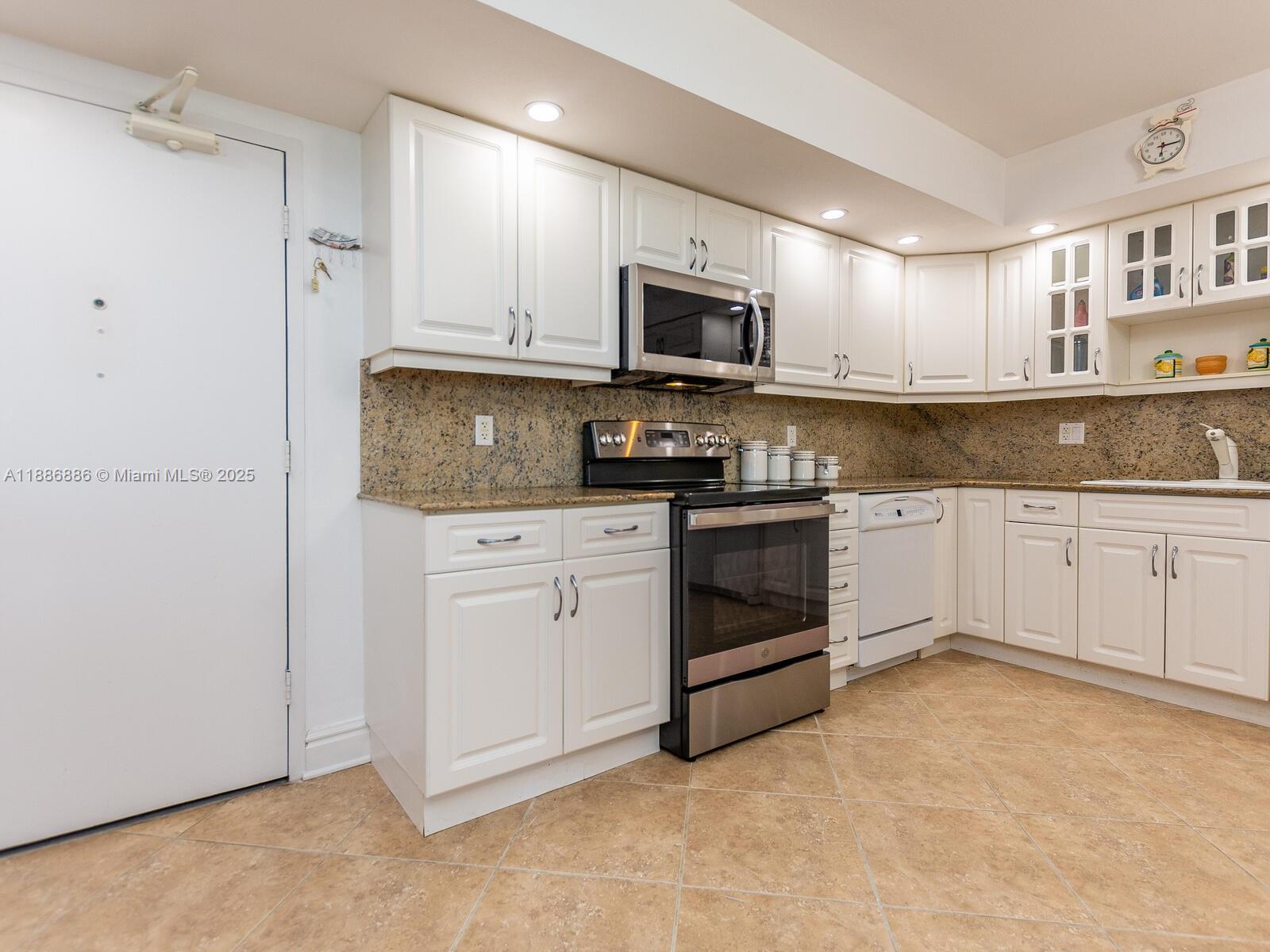 9273 Collins Avenue, Unit 703 Surfside, FL 33154 - Photo 8 of 49 a kitchen with white cabinets stainless steel appliances and sink